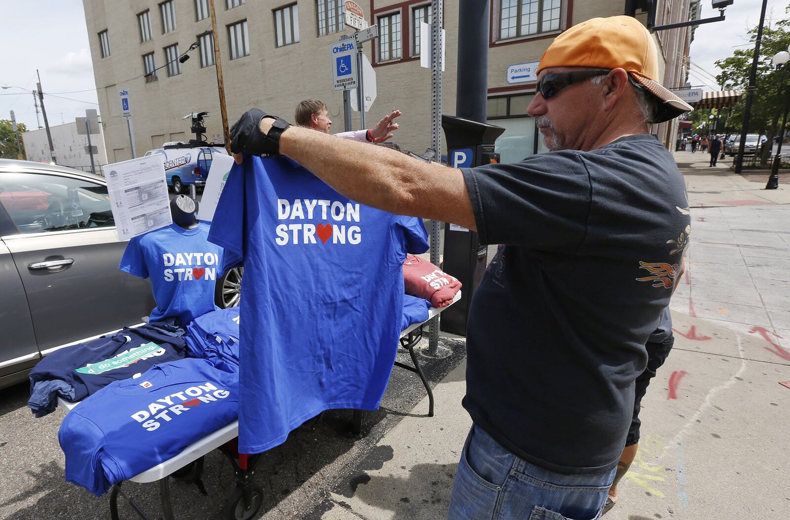 Memorials to victims of the mass shooting on August 4 have begun to shrink in the Oregon District and some business owners would like to have them removed. Many people continued to visit the memorials during the Friday lunch hour and Huber Heights resident sized up the Dayton Strong t-shirts stating, “I already have one but I came back to get one for the Mrs.” TY GREENLEES / STAFF