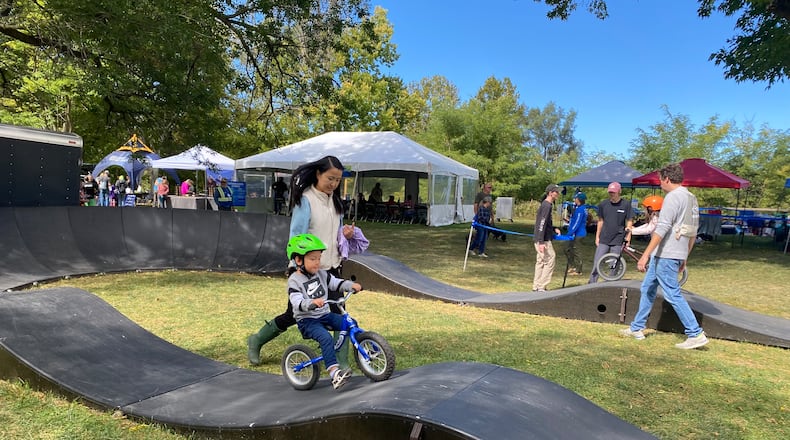 Three-year-old Theodore Chima tries biking on a track during the Wagner Subaru Outdoor Event while his mom, Mengwan Chima, helps him on Saturday, Oct. 1 at Eastwood MetroPark. Eileen McClory / Staff