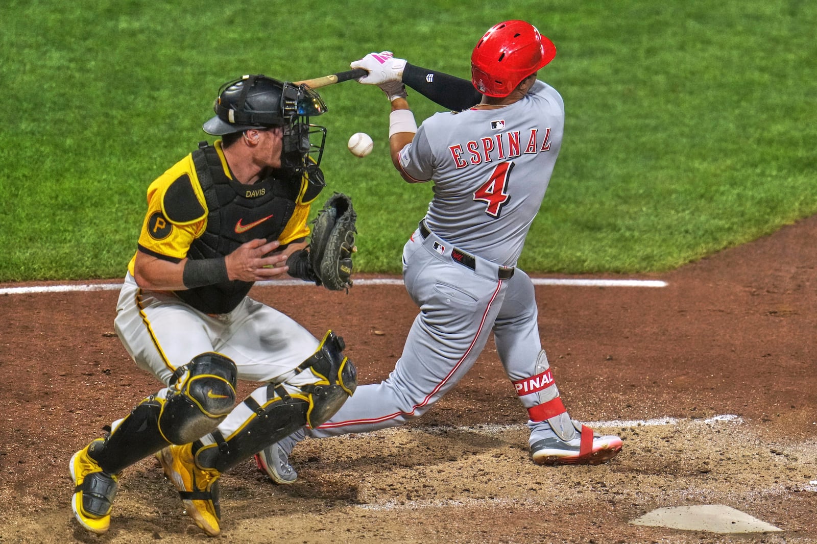 The ball pops out of the glove of Pittsburgh Pirates catcher Henry Davis, left, as he gets set to throw to second after a swing by Cincinnati Reds' Santiago Espinal (4) during the eighth inning of a baseball game in Pittsburgh, Friday, Aug. 8, 2025. (AP Photo/Gene J. Puskar)