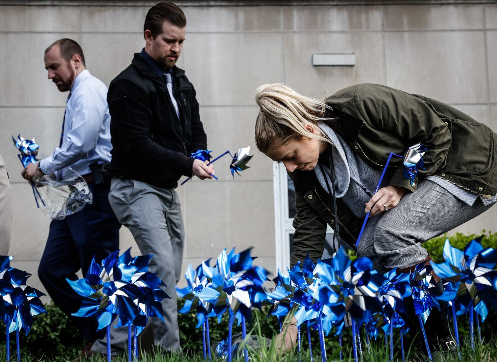 Dayton police Special Victims Unit detectives from left, Doug Thompson, Josh Bowling and Karina Sulek plant a pinwheel garden in front of the Safety Building on West Third St. in honor of Child Abuse Prevention Month. JIM NOELKER/STAFF