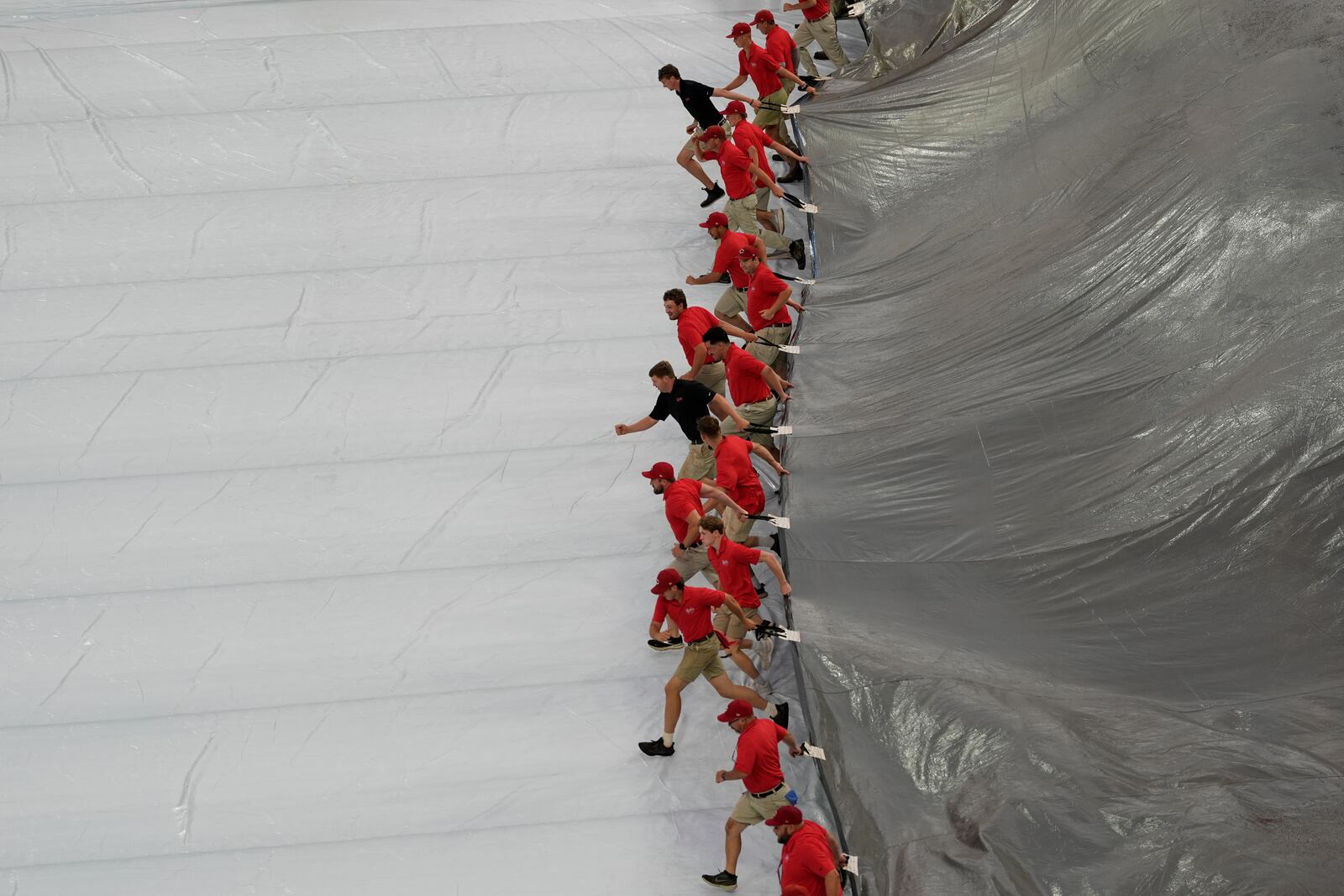 Members of the grounds crew remove a tarp from the field after a rain delay before a baseball game between the Cincinnati Reds and the Miami Marlins in Cincinnati, Monday, July 7, 2025. (AP Photo/Carolyn Kaster)