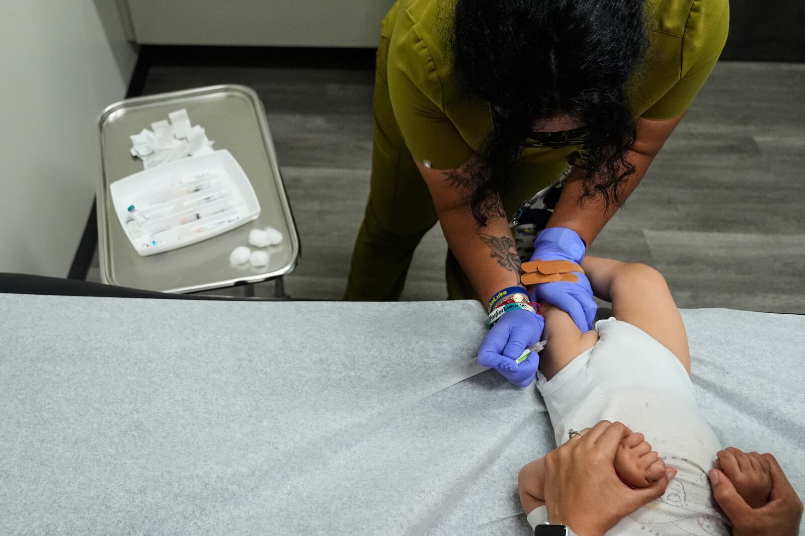 Medical assistant Citlalli Llamas, top, administers a round of vaccines to a 16-month-old boy at a CommuniCARE+OLE clinic Thursday, June 26, 2025, in Davis, Calif. (AP Photo/Godofredo A. Vásquez)