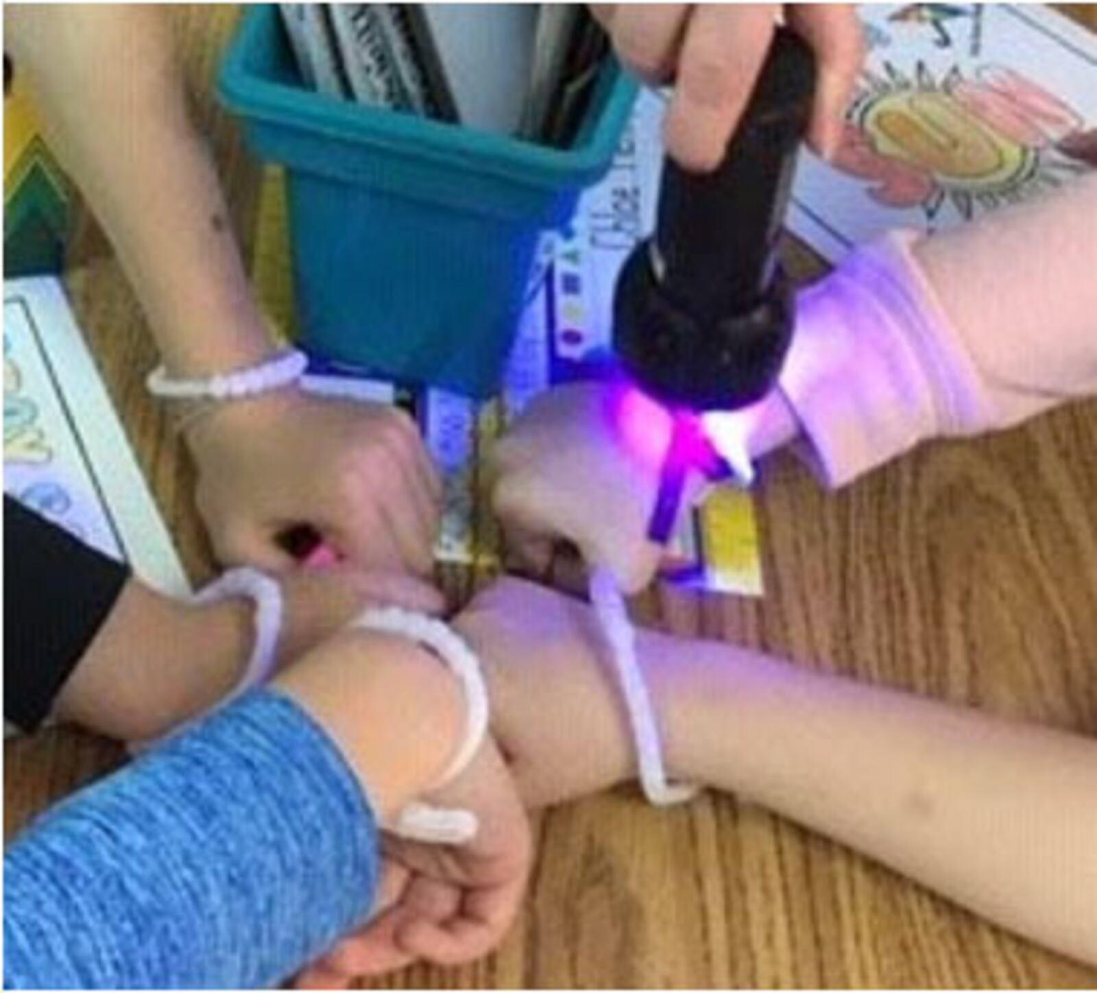First-grade students in the Wizards of Wright! program use ultraviolet beads to show the effect of UV rays during an outreach lesson in April. (Contributed photo)