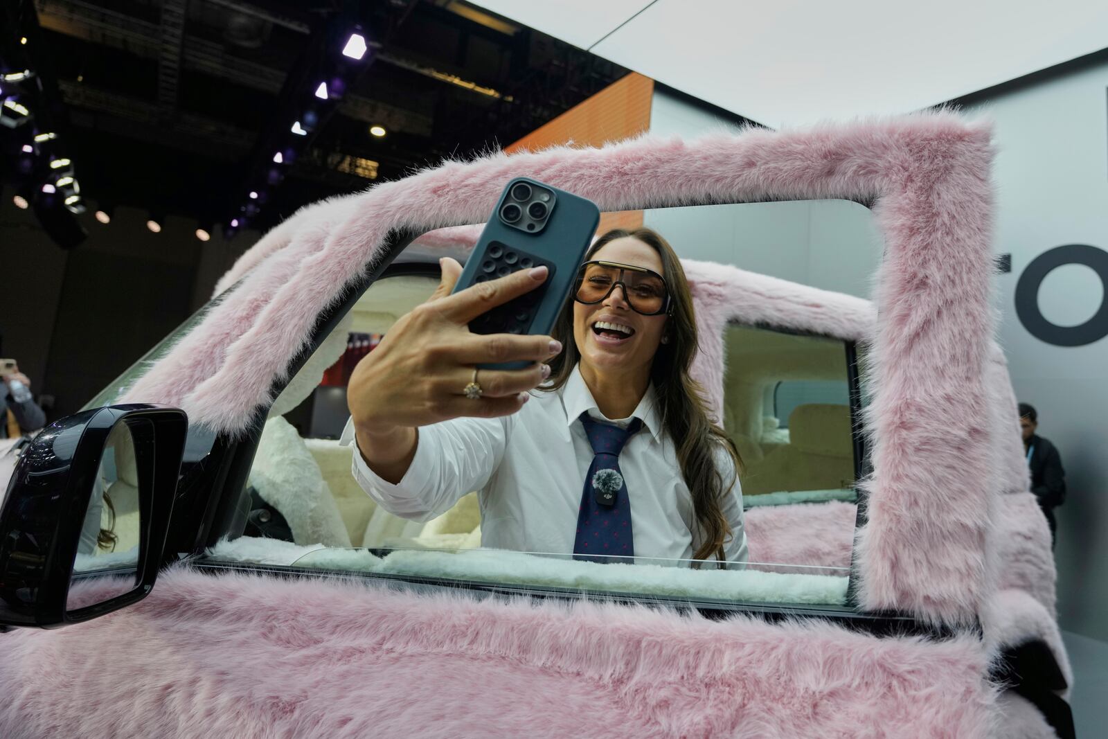 A visitor reacts to a car decked out with pink fur at the Shanghai auto show on Wednesday, April 23, 2025. (AP Photo/Ng Han Guan)