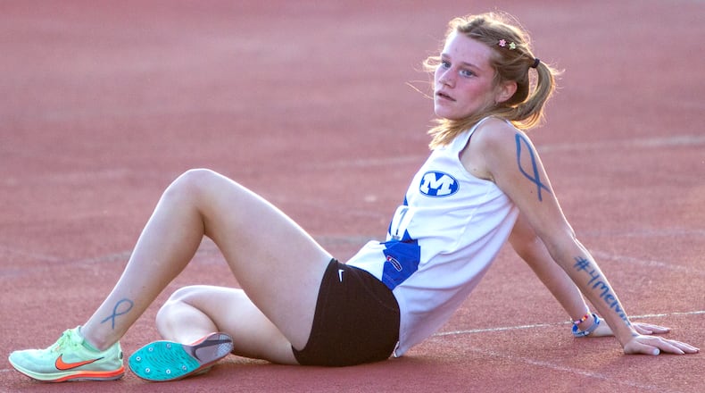 Miamisburg junior Lauren Zanotelli rests after winning the 3,200 meters at Friday's Division I regional  meet at Wayne. She and her teammates drew blue ribbons on their arms and legs in memory of head coach Melvin Johnson. Zanotelli also wrote #4melvin on her left arm. Jeff Gilbert/CONTRIBUTED