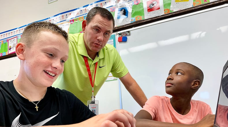 Concord Elementary School fifth grade teacher Jacob Wells, works with students, left to right, Jonah Efaw and Jax Johnson Monday Sept. 19, 2022. MARSHALL GORBY\STAFF