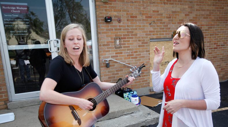 Jordan Wilson, left, and Amanda Whelden played and sang worship songs at Northridge Wesleyan Church where Pastor C. Scott Ritz held a Sunday service in the parking lot of the tornado damaged church in Harrison Twp. Ritz said the church has insurance to take care of their building but his main concern is helping the community. TY GREENLEES / STAFF
