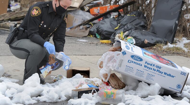 Montgomery County Environmental Enforcement Deputy Robbie Jackson looks through trash at a illegal dump site on Bender Ave. in Dayton on Thursday, Feb. 4, 2021. MARSHALL GORBY/STAFF