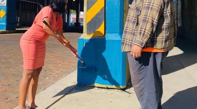 Lead mural artist, Dave Scott and a volunteer, get started on what will be the Oregon District bridge mural.