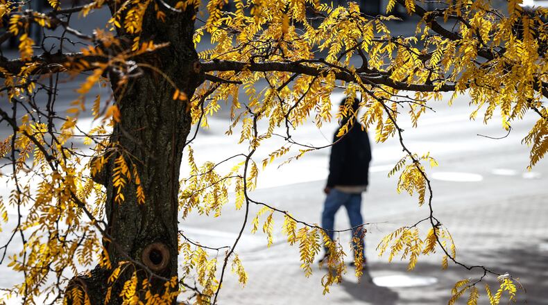 A pedestrian walks across Third Street in Dayton Monday morning October 17, 2022. Cooler weather is moving into the Miami Valley this week triggering a frost warning.