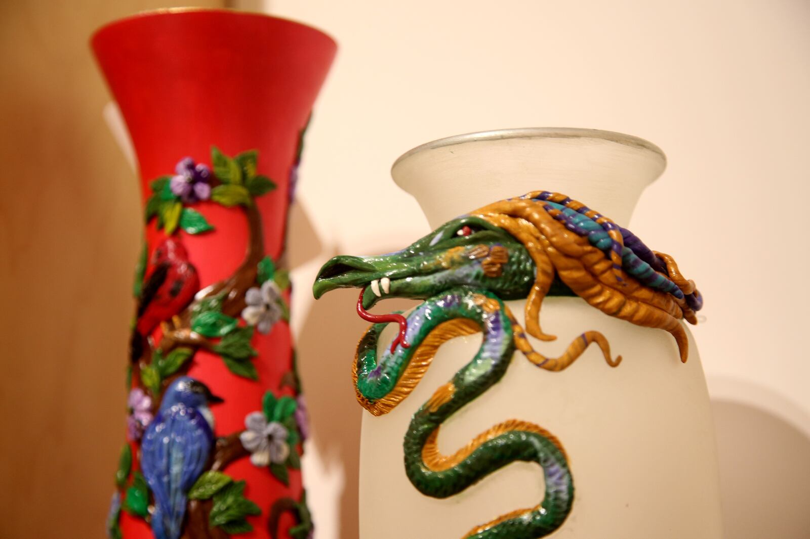 Ornate and colorful hand sculpted glass vases by artist Roxanne Howard are a one-of-a-kind piece. A dragon wraps around a white vase, birds and flowers rest on a slender red vase and a bright orange Phoenix rises on another. Prices range from $105-$150. LISA POWELL / STAFF