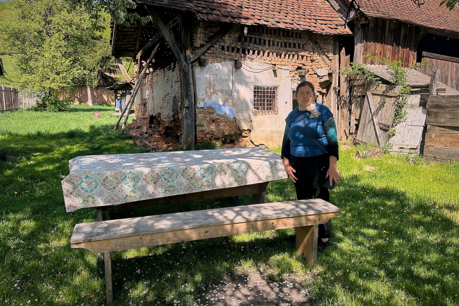Liliana Cosurean, 54, stands in the yard of her home, in the village of Floresti, in Romania's central Transylvania region, Thursday, April 24, 2025. (AP Photo/Stephen McGrath)