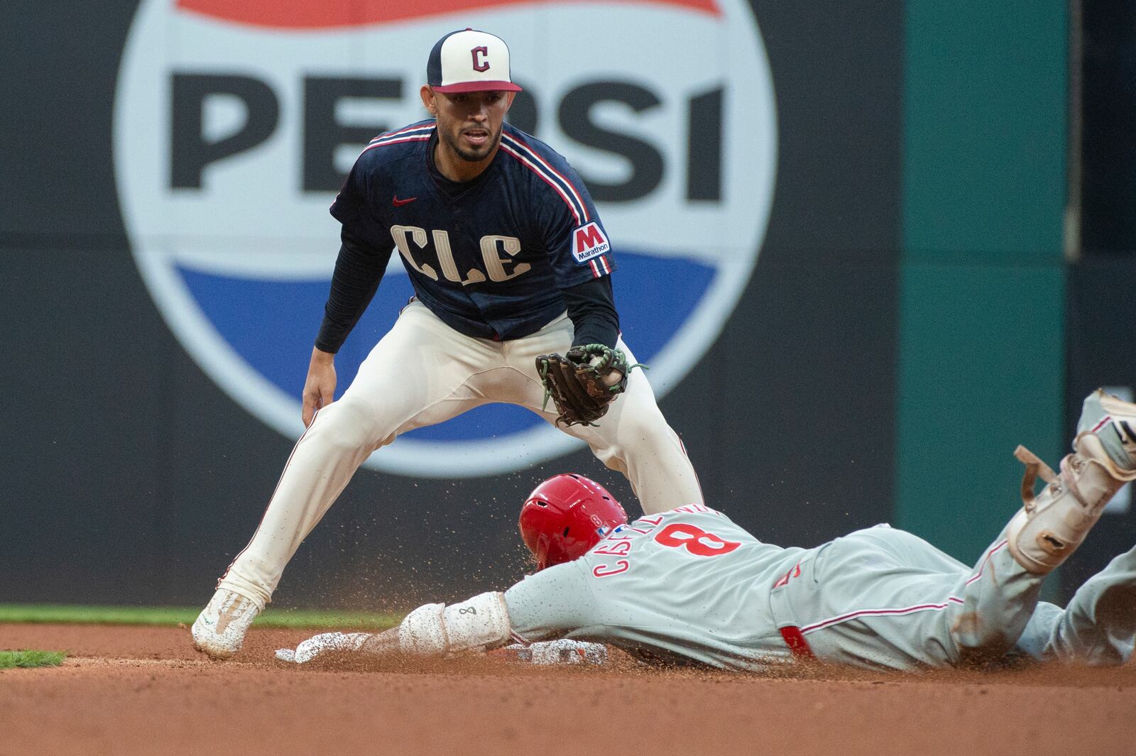 Cleveland Guardians' Gabriel Arias, top, prepares to tag out Philadelphia Phillies' Nick Castellanos (8) during the fourth inning of a baseball game Friday, May 9, 2025, in Cleveland. (AP Photo/Phil Long)