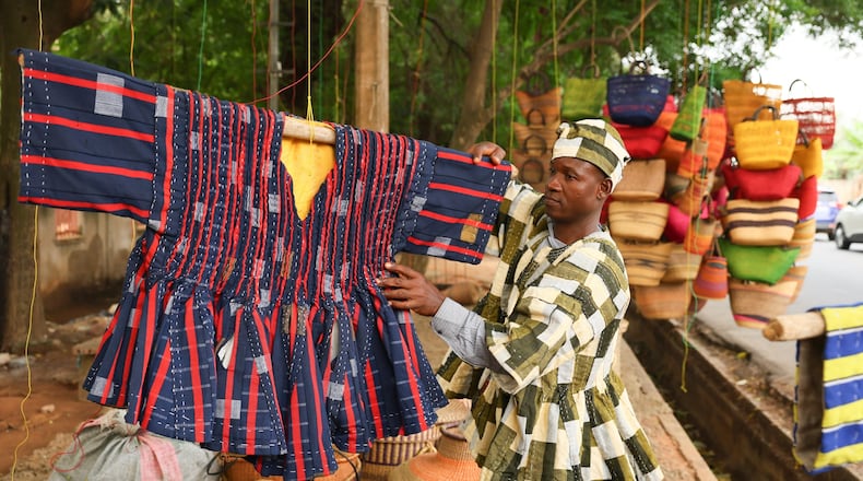 Clement Azaabire hangs traditional fugu garments under a tree on display for sale along a street in Accra, Ghana, Wednesday, Feb. 18, 2026. (AP Photo/Tsraha Yaw)