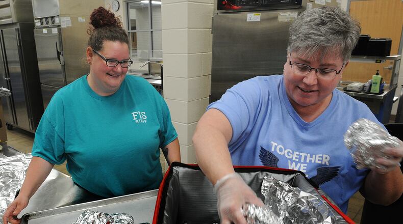 Fairborn City School staff, Left, Kristine Van Meter, and Jackie Hazelett, place warm chicken sandwiches into thermal bags for free lunches at the Fairborn Primary School and to be delivered to the Fairborn library for free lunches, Thursday 23, 2022. MARSHALL GORBY\STAFF
