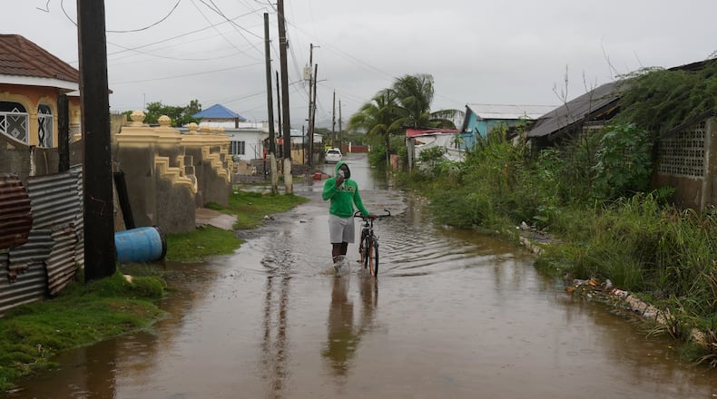 A man wades through a flooded street ahead of the forecasted arrival of Hurricane Melissa in Old Harbour, Jamaica, Monday, Oct. 27, 2025. (AP Photo/Matias Delacroix)