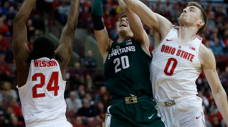 Michigan State guard Matt McQuaid, center, goes up to shoot between Ohio State forward Andre Wesson, left, and center Micah Potter during the first half of an NCAA college basketball game in Columbus, Ohio, Sunday, Jan. 7, 2018. (AP Photo/Paul Vernon)