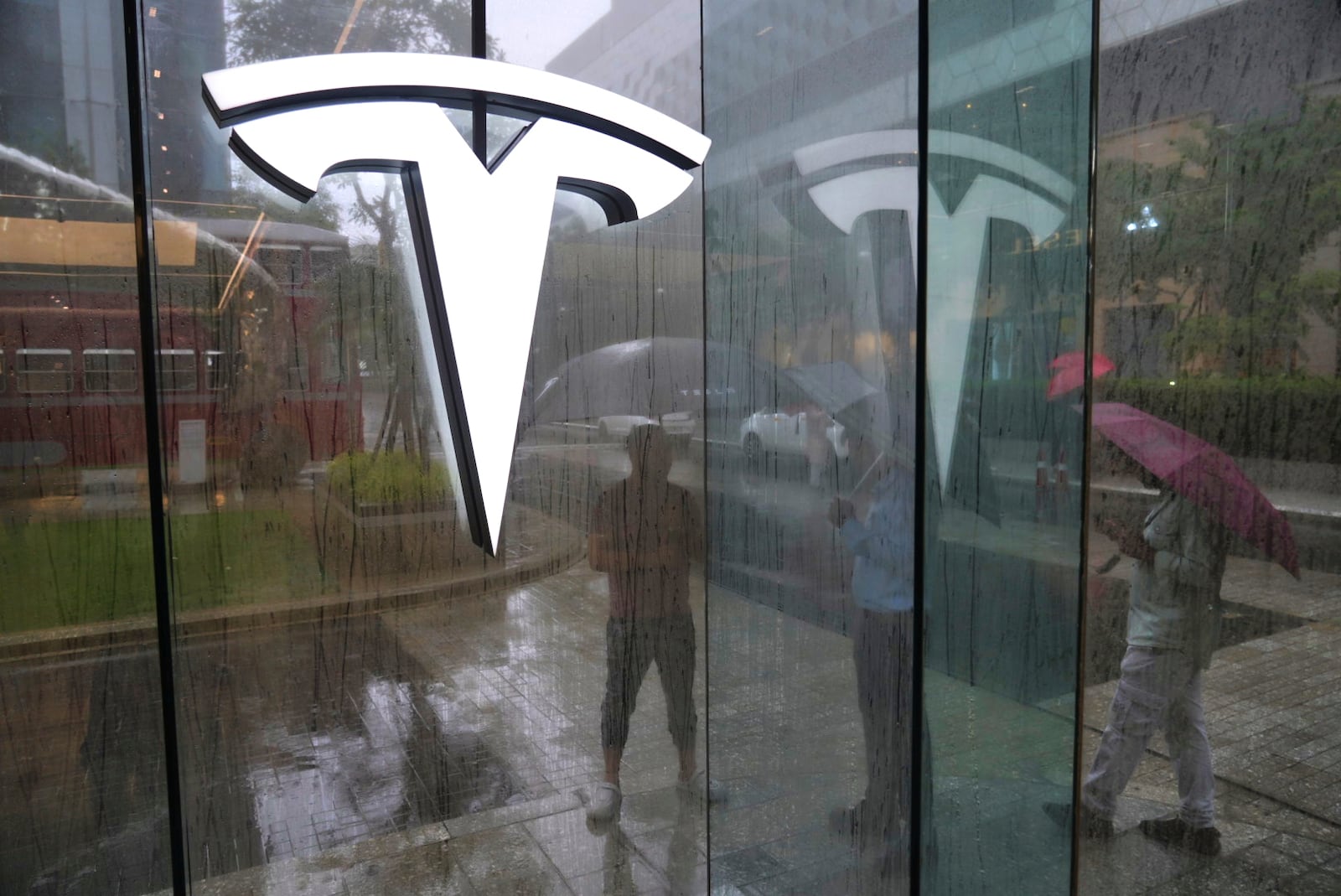 Private security guards stand amidst rain outside India's first TESLA showroom in Mumbai, India, Tuesday, July 15, 2025. (AP Photo/Rafiq Maqbool)