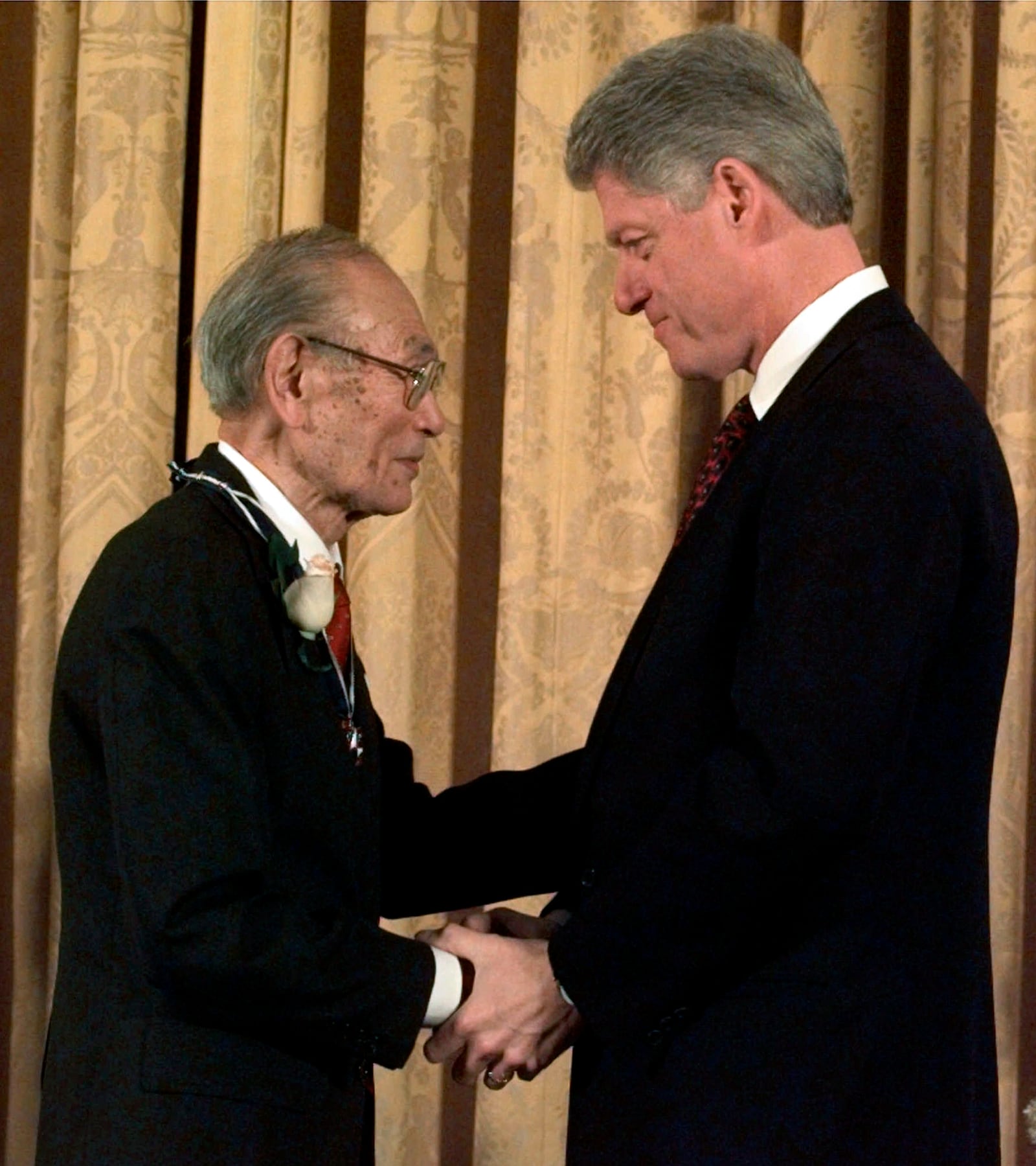 FILE - In this Jan. 15, 1998 file photo, then President Clinton presents Fred Korematsu with a Presidential Medal of Freedom during a ceremony at the White House. Arizona is honoring late civil rights icon Korematsu, whose fight against Japanese American internment went all the way to the U.S. Supreme Court. Gov. Doug Ducey on Thursday, April 15, 2021, signed legislation establishing a “Fred Korematsu Day of Civil Liberties and the Constitution” on Jan. 30, Korematsu’s birthday. The legislation comes as the nation continues to see a rise in anti-Asian crimes that started with the pandemic. (AP Photo/Dennis Cook, File)
