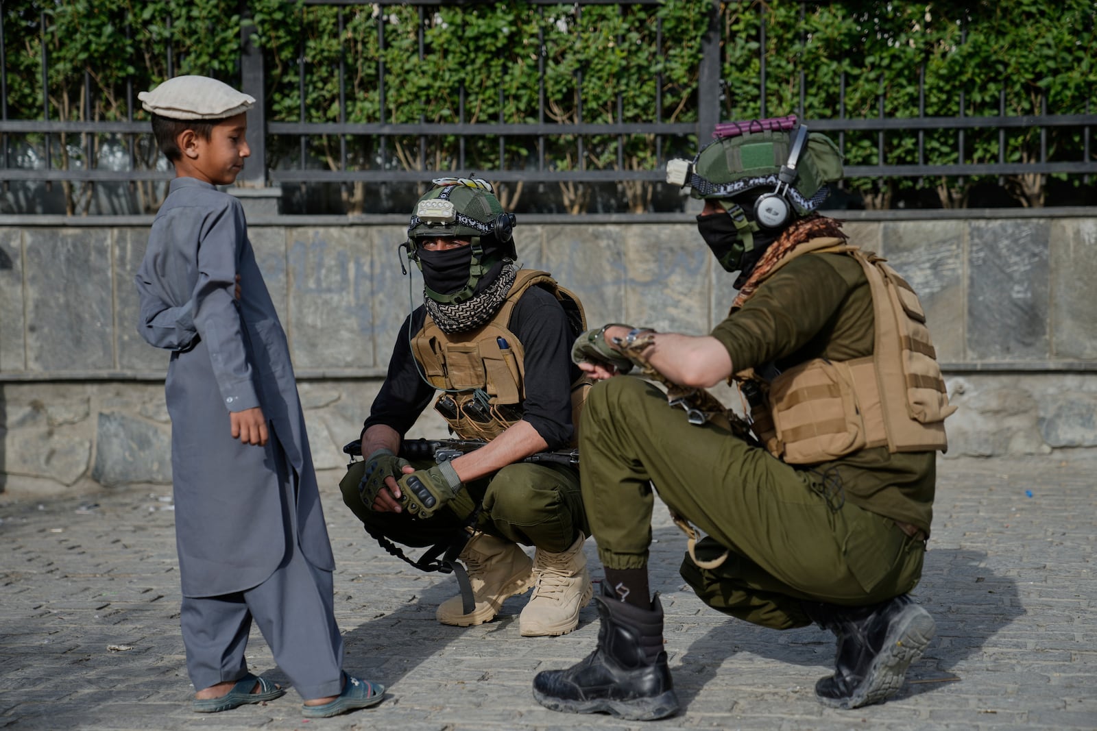 Taliban fighters speak with a boy during the Eid al-Adha prayers the Shah-Do Shamshira Mosque in Kabul, Afghanistan, Saturday, June 7, 2025. (AP Photo/Ebrahim Noroozi)