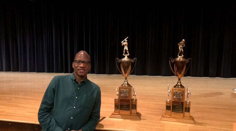 New York times best-selling author author, award-winning journalist and Miami University former basketball player, grad and distinguished visiting professor Wil Haygood at East High with championship trophies from 1968-69. Haygood will appear three times in Dayton over the next month (as part of UD Speaker Series on Tuesday, as part of Dayton Literary Peace Prize Community Conversations on Oct. 11 at the Dayton Metro Library and at Books a Million in The Greene Oct. 26. Tom Archdeacon/STAFF