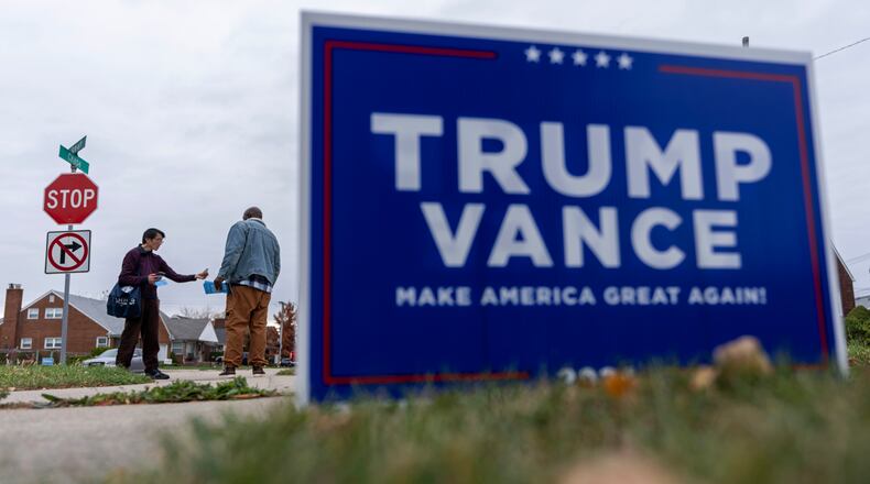 Campaign volunteers for Democratic presidential nominee Vice President Kamala Harris, Andy Lei, left, and Raheem St. John, come across a sign for Republican presidential nominee former President Donald Trump on the lawn of a registered Democrat while canvassing a neighborhood for voters, Monday, Nov. 4, 2024, in Dearborn, Mich. (AP Photo/David Goldman)