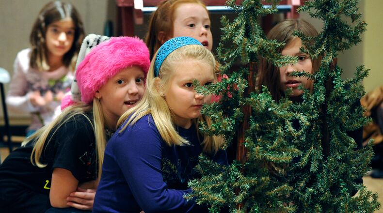 Cautious Munchkins hide among the trees in the Muse Machine's production of "The Wizard of Oz."