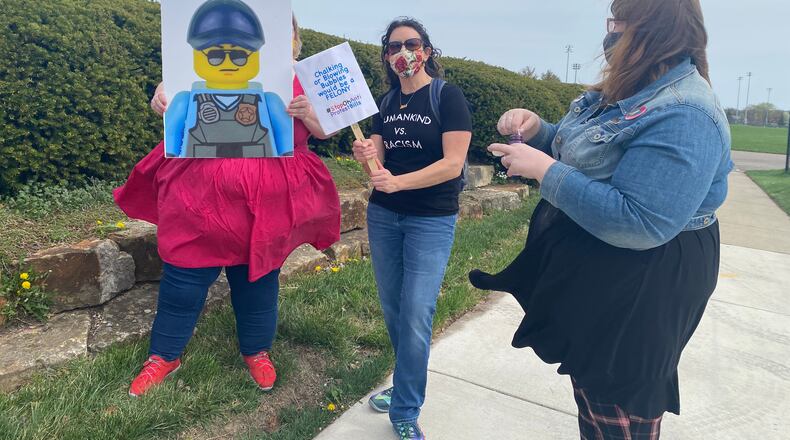 Michael Null, left, Michele Berry, center and Jennifer Damon, right, demonstrate in front of Delco Park in Kettering on Saturday. EILEEN MCCLORY / STAFF