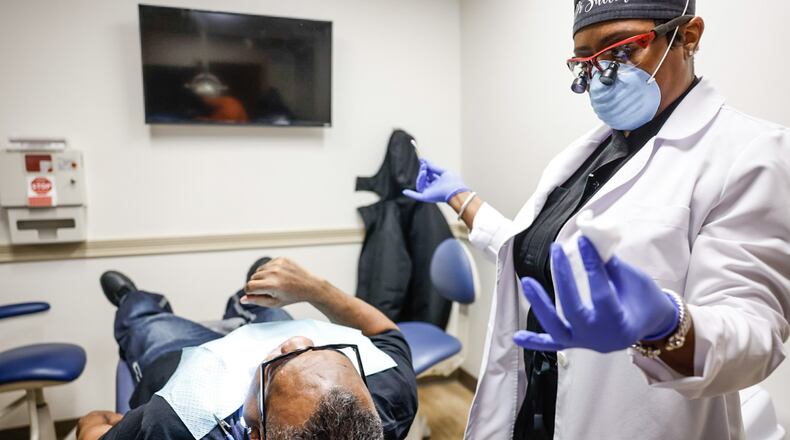 Good Neighbor House dentist Dr. Shanetta Sutton works on a patient at the facility on East First Street. JIM NOELKER/STAFF