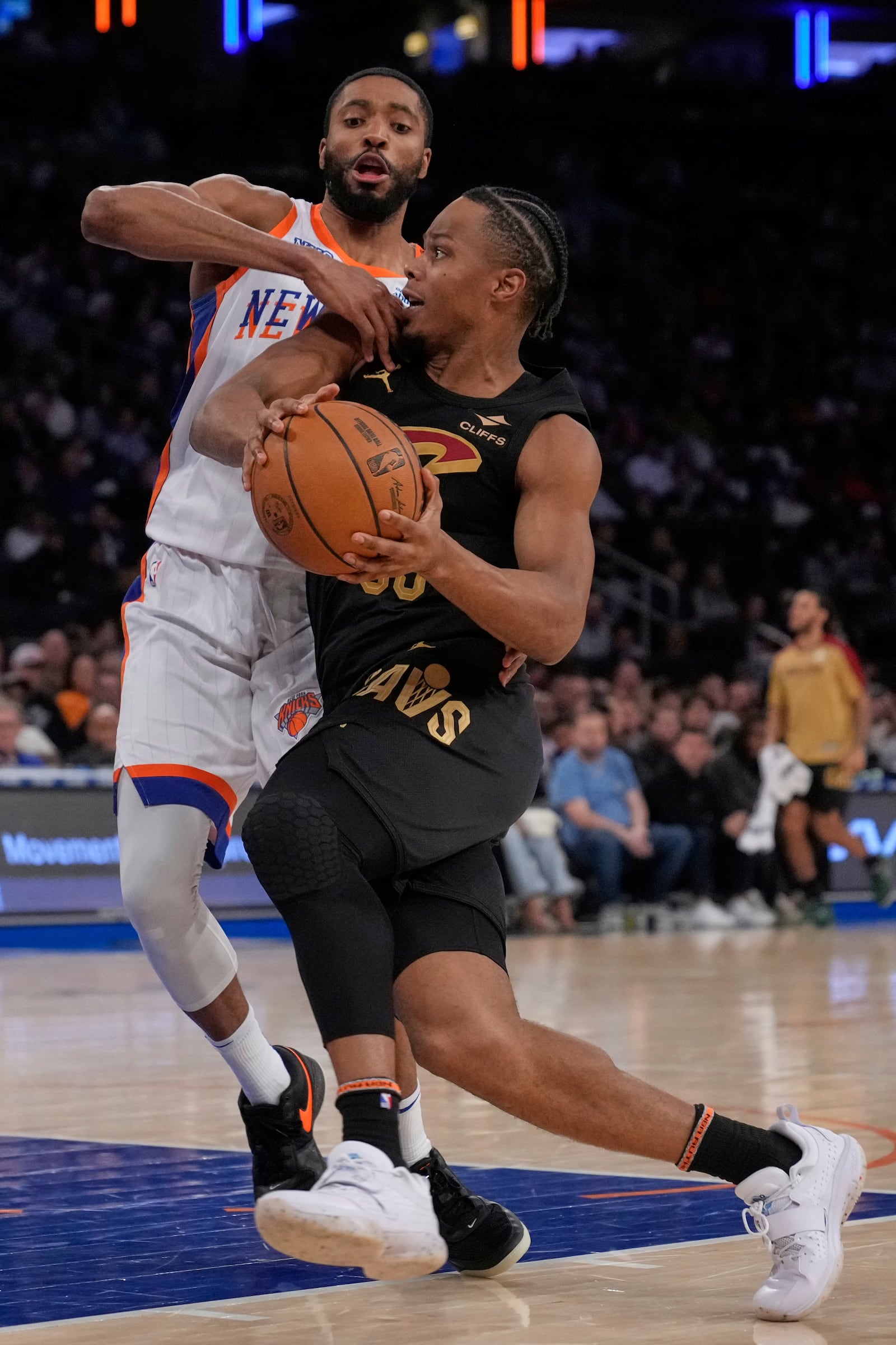 Cleveland Cavaliers' Isaac Okoro, right, drives past New York Knicks' Mitchell Robinson during the first half of an NBA basketball game Friday, April 11, 2025, in New York. (AP Photo/Seth Wenig)