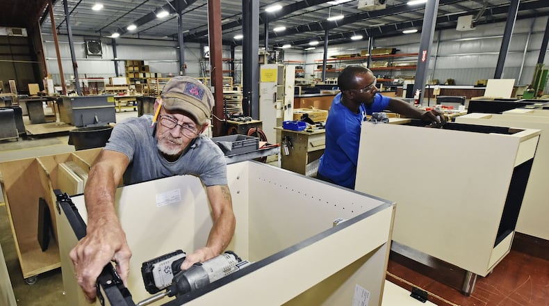Jesse Combs, left, and Devinn Parms build cabinets at Custom Millcraft Corporation Tuesday, Oct. 10 in West Chester Twp. The fixture manufacturer specializes in high-end fixture work and complete millwork packages for retail, restaurant, banking and healthcare industries. The company is expanding its workforce. NICK GRAHAM/STAFF