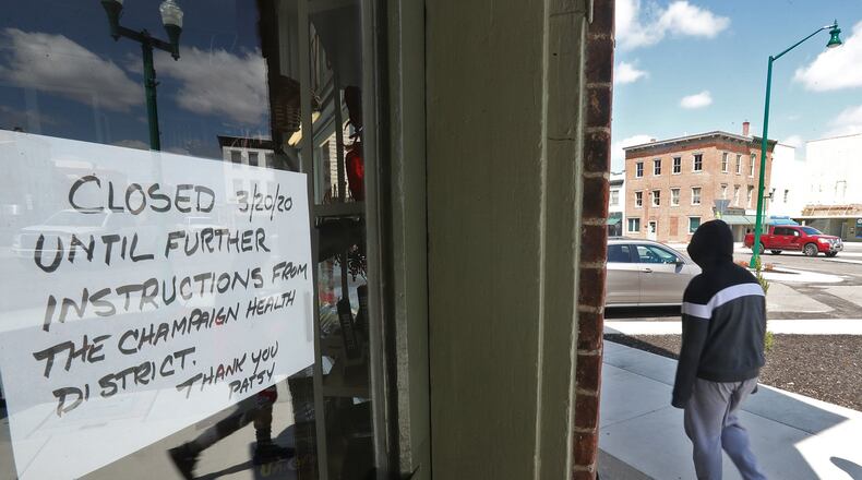 A pedestrian walks down the sidewalk past all the “Closed” signs on businesses in downtown Urbana in mid-April. BILL LACKEY/STAFF