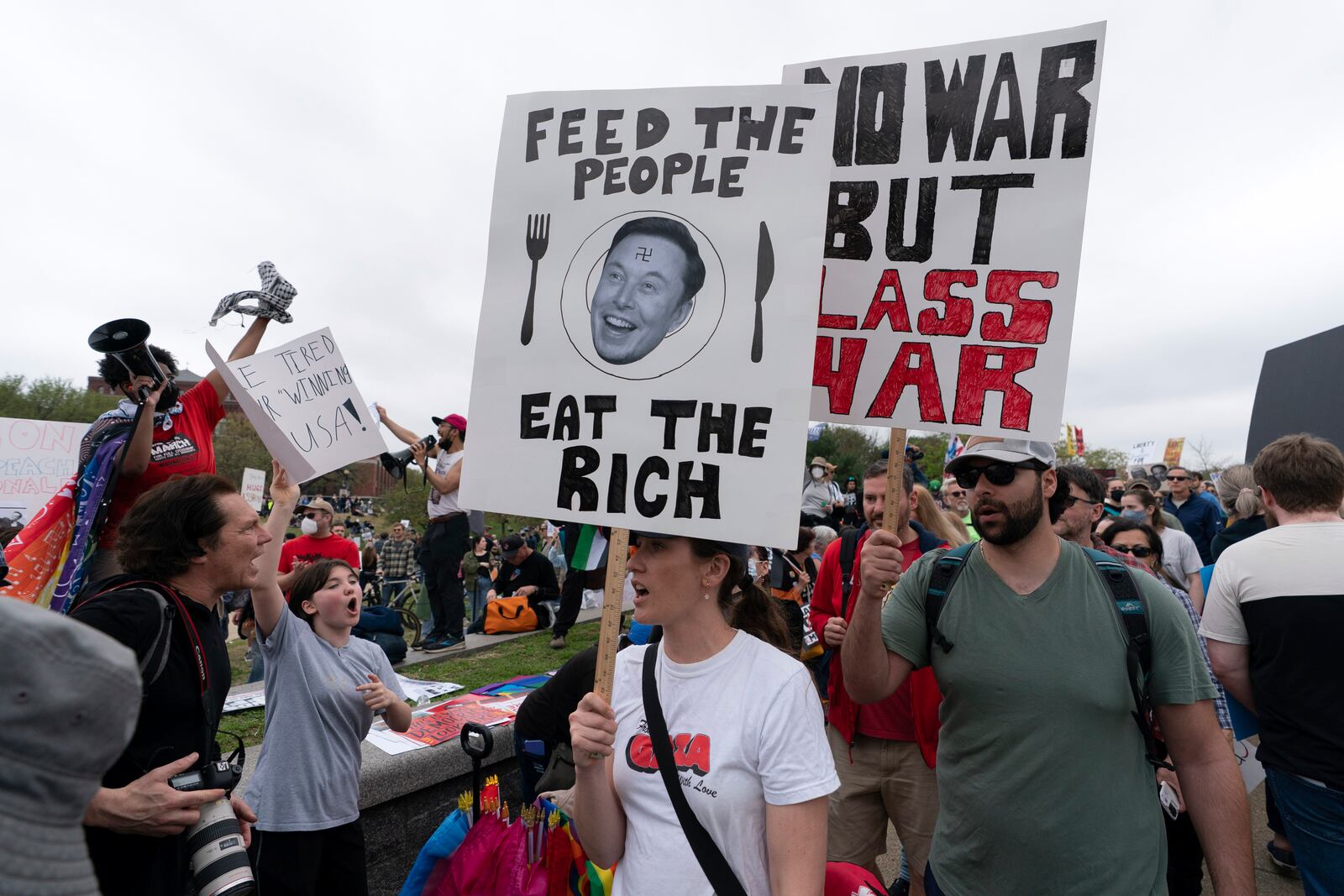 Demonstrators carry signs during the "Hands Off!" protests against President Donald Trump and Elon Musk at the Washington Monument in Washington, Saturday, April 5, 2025. (AP Photo/Jose Luis Magana)