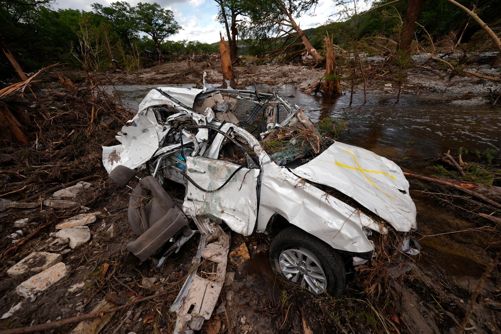 A destroyed vehicle sits next to the Guadalupe River on Wednesday, July 9, 2025, in Hunt, Texas, after a flash flood swept through the area. (AP Photo/Gerald Herbert)