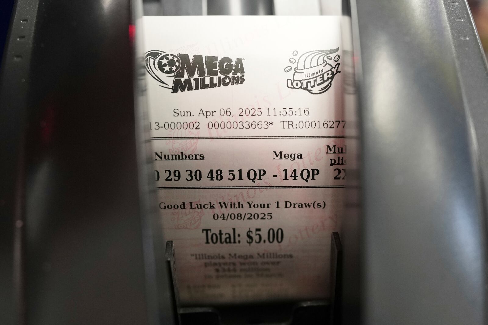 A Mega Millions lottery ticket is printed out of a lottery machine at Mares Mart in Chicago, Sunday, April 6, 2025. (AP Photo/Nam Y. Huh)
