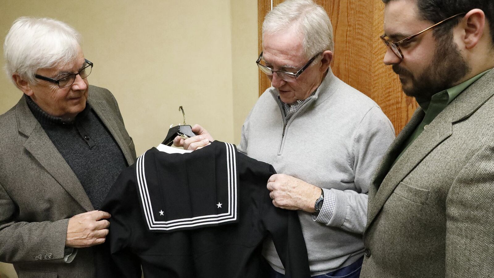 Tony Hannon, left, and his brother, Tom, center, and nephew Ryan King look over the replica of their uncles Navy uniform Monday. Their uncle, William “Billy” Welch, was killed in pearl harbor and his body was just recently identified and given a soldier’s funderal at Calvary Cemetary in Clark County. The Navy presented the uniform to the family when Welch’s remains were returned. Bill Lackey/Staff