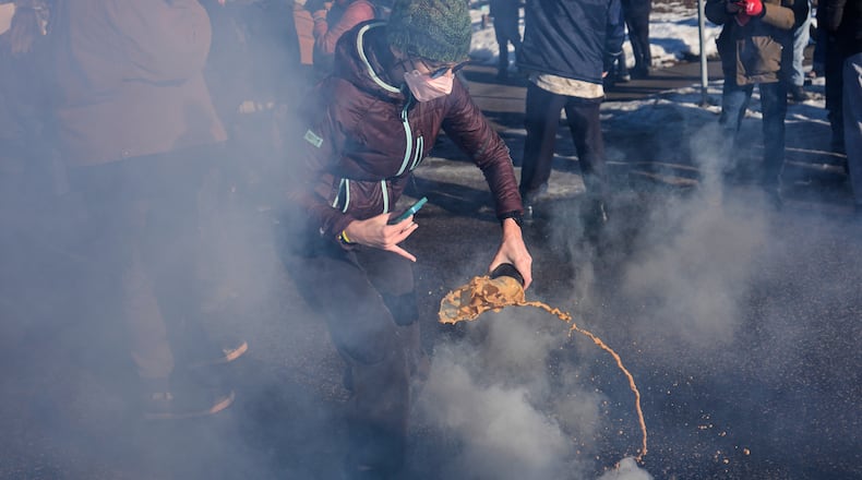 A protester grabs a tear gas grenade deployed by federal immigration officers near the scene where Renee Good was fatally shot by an ICE officer last week, Tuesday, Jan. 13, 2026, in Minneapolis. (AP Photo/John Locher)