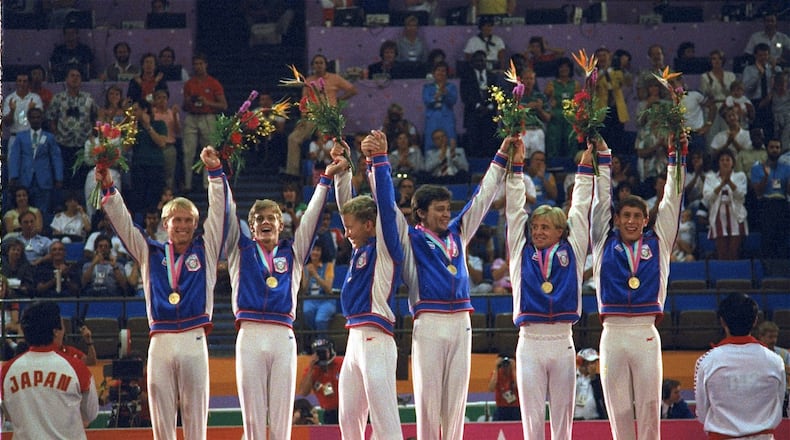 FILE - Members of the U.S. gymnastics team, from left: Bart Conner, Peter Vidmar, Jim Hartung, Mitch Gaylord, Scott Johnson and Tim Daggett, celebrate their gold medals as they stand on the winners' platform July 31, 1984 after they defeated world champion China to win the first U.S. gold medal in gymnastics in 80 years. (AP Photo/Lionel Cironneau, file)