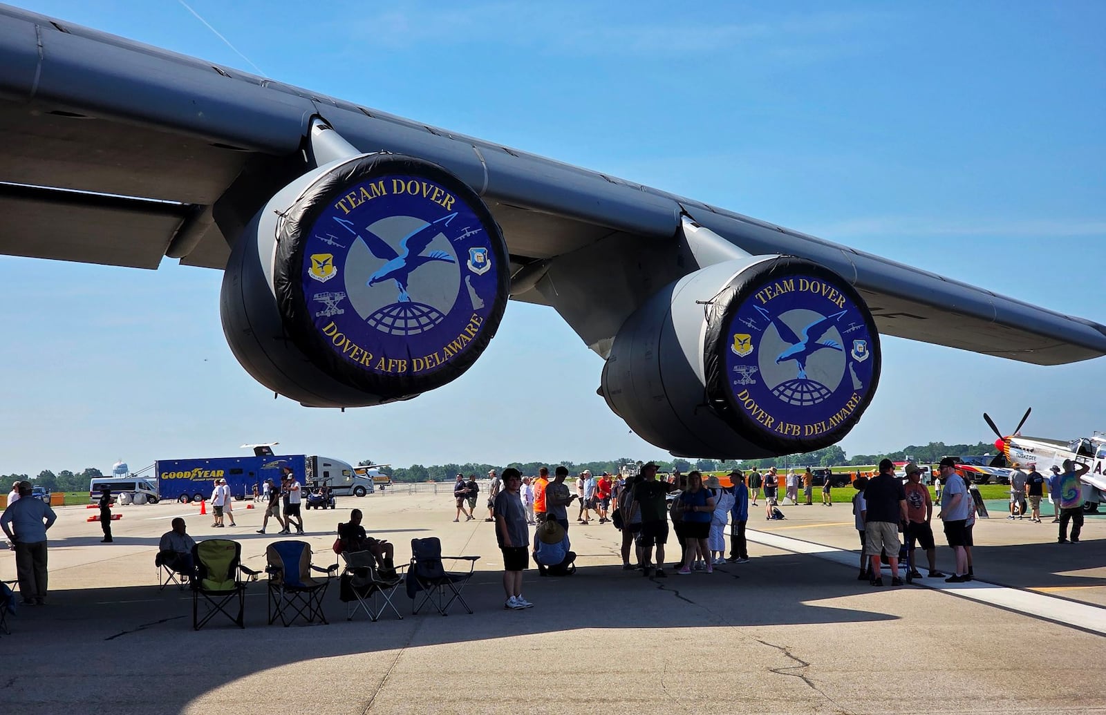 Attendees use the giant wing of a U.S. Air Force C-5M for shade during the CenterPoint Energy Dayton Air Show Saturday, June 21, 2025 at Dayton International Airport. NICK GRAHAM/STAFF