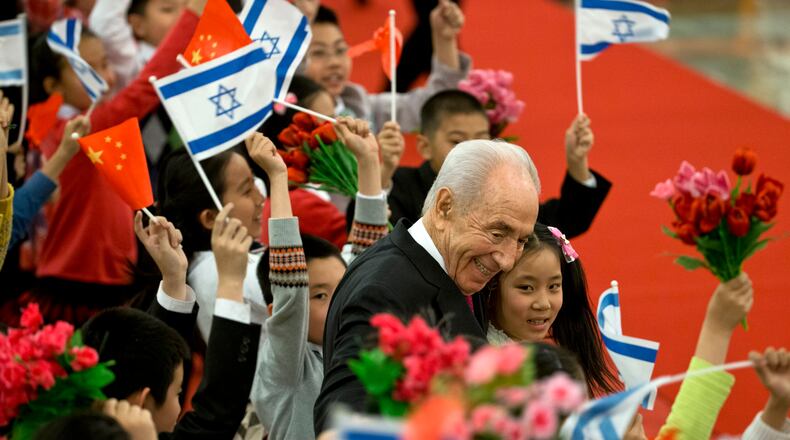 FILE- In this April 8, 2014, file photo, Israeli President Shimon Peres, center, hugs Chinese children during a welcome ceremony held by Chinese president Xi Jinping at the Great Hall of the People in Beijing. Shimon Peres, a former Israeli president and prime minister, whose life story mirrored that of the Jewish state and who was celebrated around the world as a Nobel prize-winning visionary who pushed his country toward peace, has died, the Israeli news website YNet reported early Wednesday, Sept. 28, 2016. He was 93. (AP Photo/Alexander F. Yuan, File)