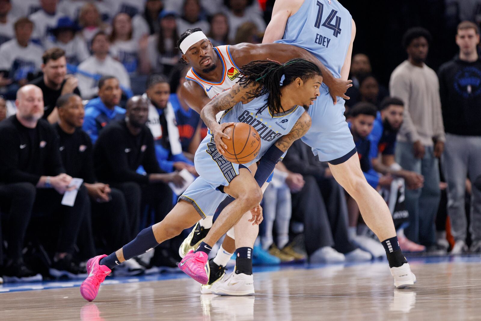 Memphis Grizzlies guard Ja Morant, front, drives past Oklahoma City Thunder guard Luguentz Dort, upper left, as Grizzlies center Zach Edey (14) screens during the first half in Game 1 of an NBA first-round playoff series, Sunday, April 20, 2025, in Oklahoma City. (AP Photo/Nate Billings)
