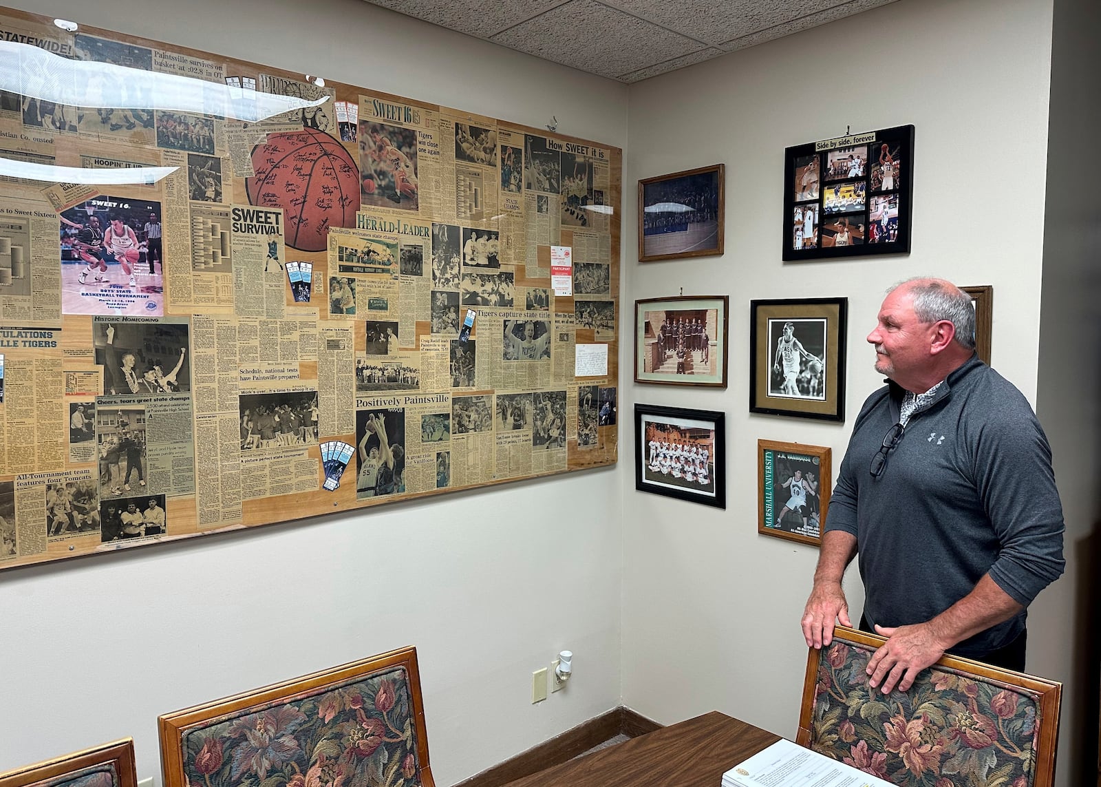 Paintsville, Ky. Mayor Bill Mike Runyon stands in his office and looks at newspapers clippings from his days as a state championship high school basketball coach, Friday, May 16, 2025. (AP Photo/Bill Barrow)