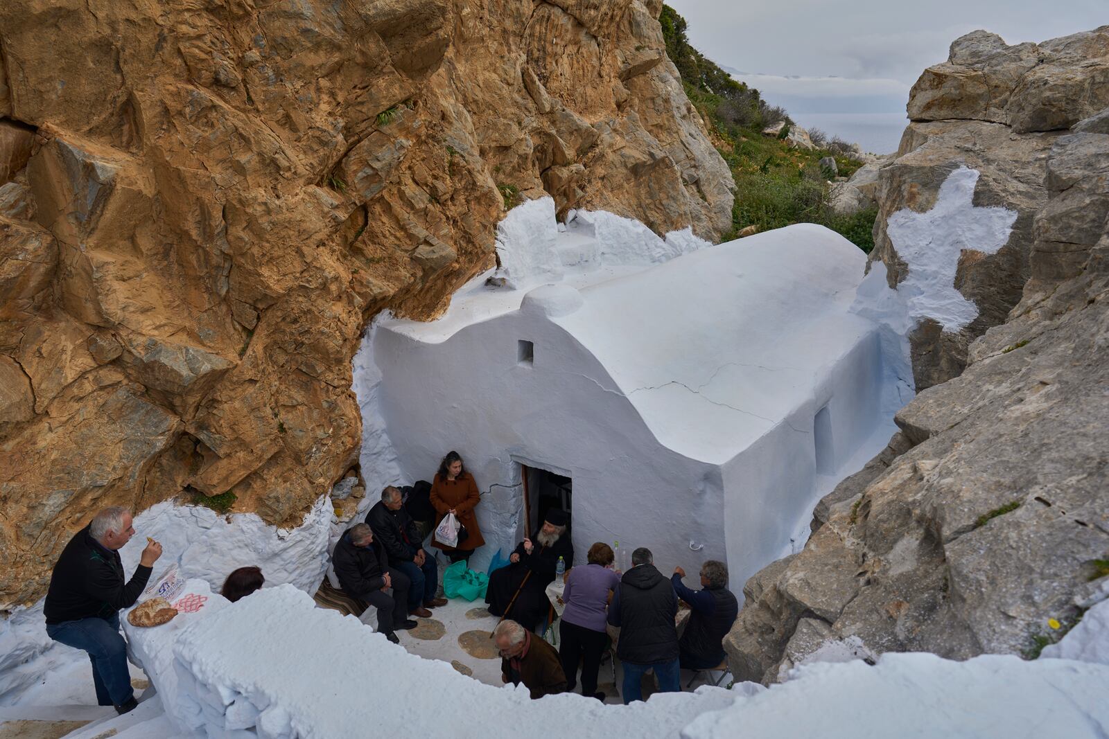 Orthodox Christian monk Father Spyridon of Amorgos, center, talks with islanders after the Divine Liturgy in the chapel of Panagia Evangelistria, in Amorgos island, Greece, on Tuesday, March 25, 2025. (AP Photo/Petros Giannakouris)