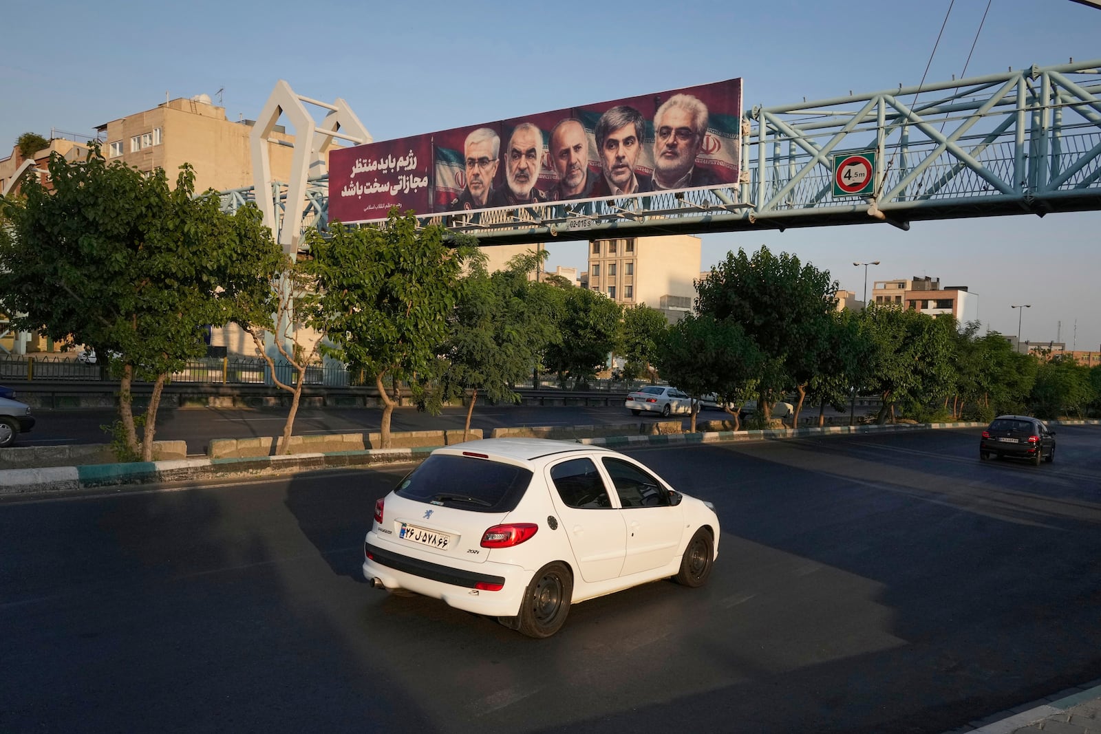 Vehicles drive past a billboard displaying images of top Iranian commanders and scientists killed in Israeli strikes early Friday, in Tehran, Iran, Friday, June 13, 2025. (AP Photo/Vahid Salemi)