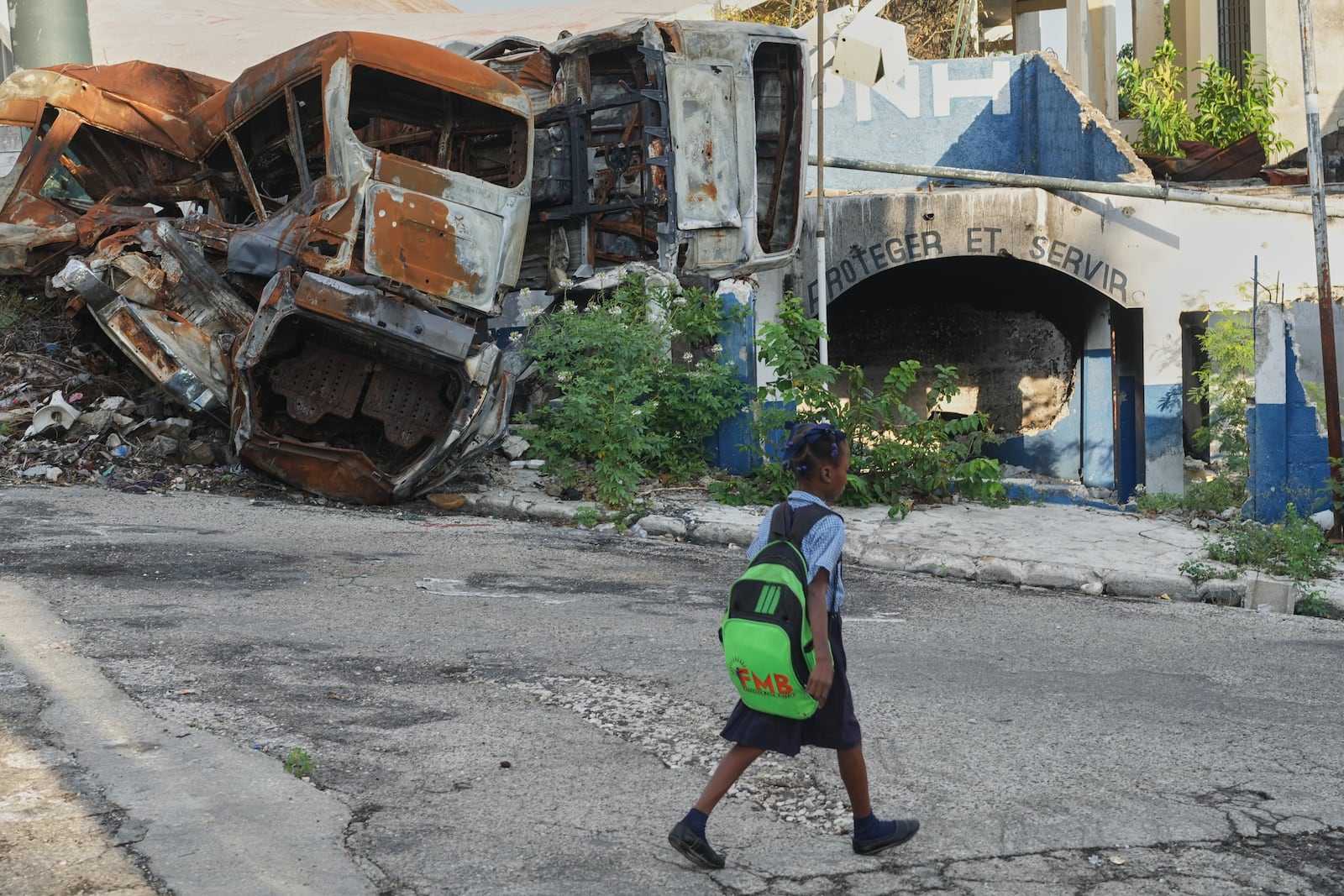 A student walks past a police station that was set on fire by armed gangs in the Delmas neighborhood of Port-au-Prince, Haiti, Tuesday, Feb. 24, 2026. (AP Photo/Odelyn Joseph)