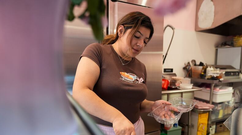 Andrea Melendez cuts a piece of cake for a customer at Pink Flores Bakery and Cafe, Wednesday, Nov. 19, 2025, in the Pilsen neighborhood of Chicago. (AP Photo/Erin Hooley)