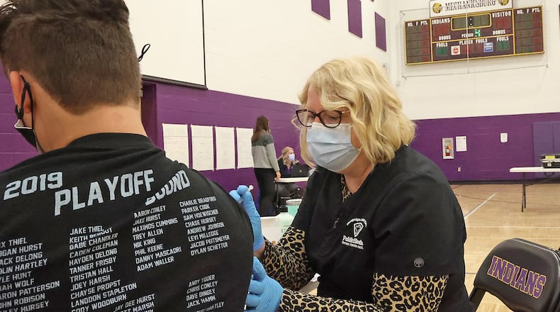 Hope Stickley, a nurse from the Champaign County Health Department, gives a student the COVID vaccine during a COVID clinic in one of  Mechanicsburg High School's gymnasiums in April.  The Ohio Department of Health is strongly recommending that unvaccinated students and staff wear masks when school starts. BILL LACKEY/STAFF