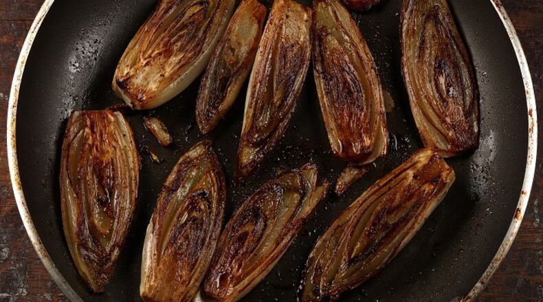 Heads of Belgian endive are sliced in half, then crisped in butter and olive oil, and finished with a crumble of rich cheese. (E. Jason Wambsgans/Chicago Tribune/TNS)