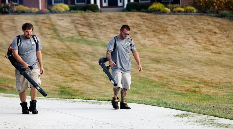 Dunham's Lawn Care employees Hayden Pond and Joshua Jackson blow grass off the driveway of a Greene County customer Wednesday, Sept. 25, 2024. The drought that has swept through Ohio and worsened over the past several weeks has turned area lawns brown and brittle. MARSHALL GORBY/STAFF