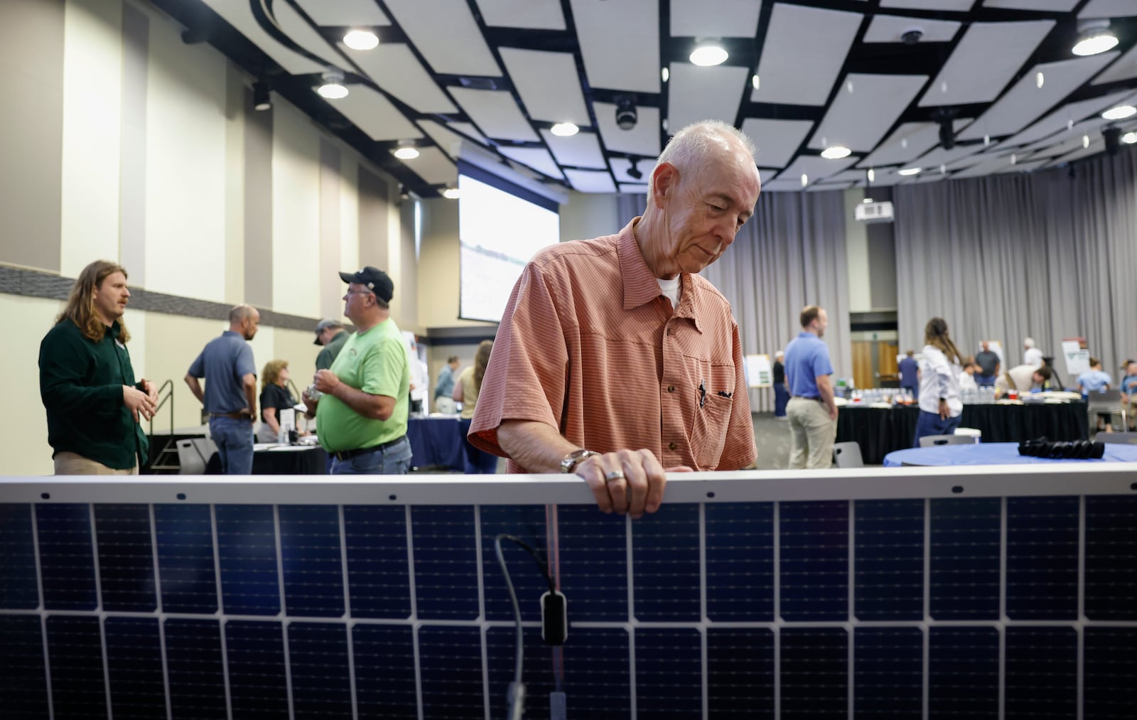 Robert Shipley, center, of Springfield, looks at a solar panel during a public information meeting held by Invenergy on Tuesday, July 8, 2025, at Hollenebeck Center to get feedback on the 180-megawatt Sloopy Solar Energy Center. JOSEPH COOKE/STAFF